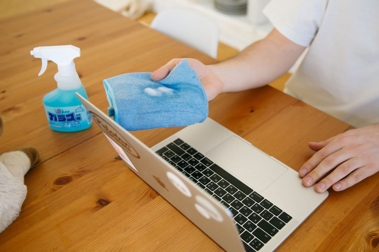 Laptop and desk surface being disinfected with spray and cloth