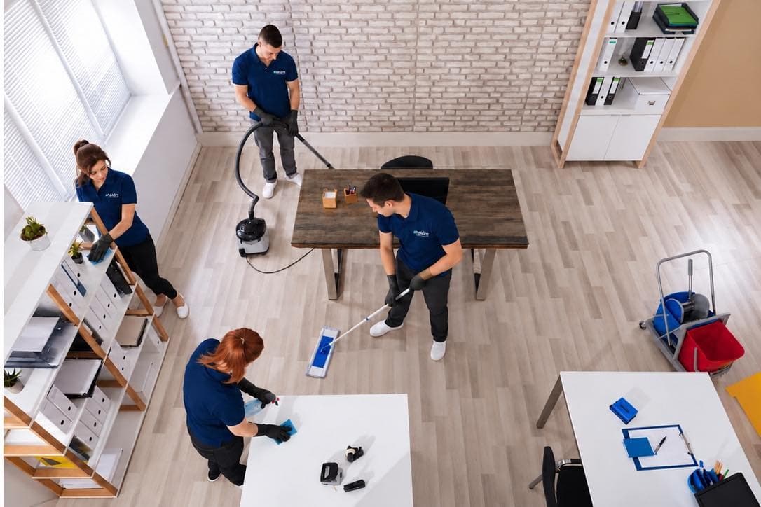 Taïdra Cleaning team in navy uniforms vacuuming, mopping and wiping surfaces in a bright office