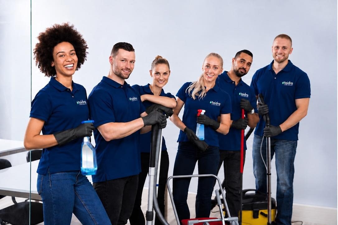 Smiling Taïdra Cleaning team in navy uniforms holding professional cleaning equipment