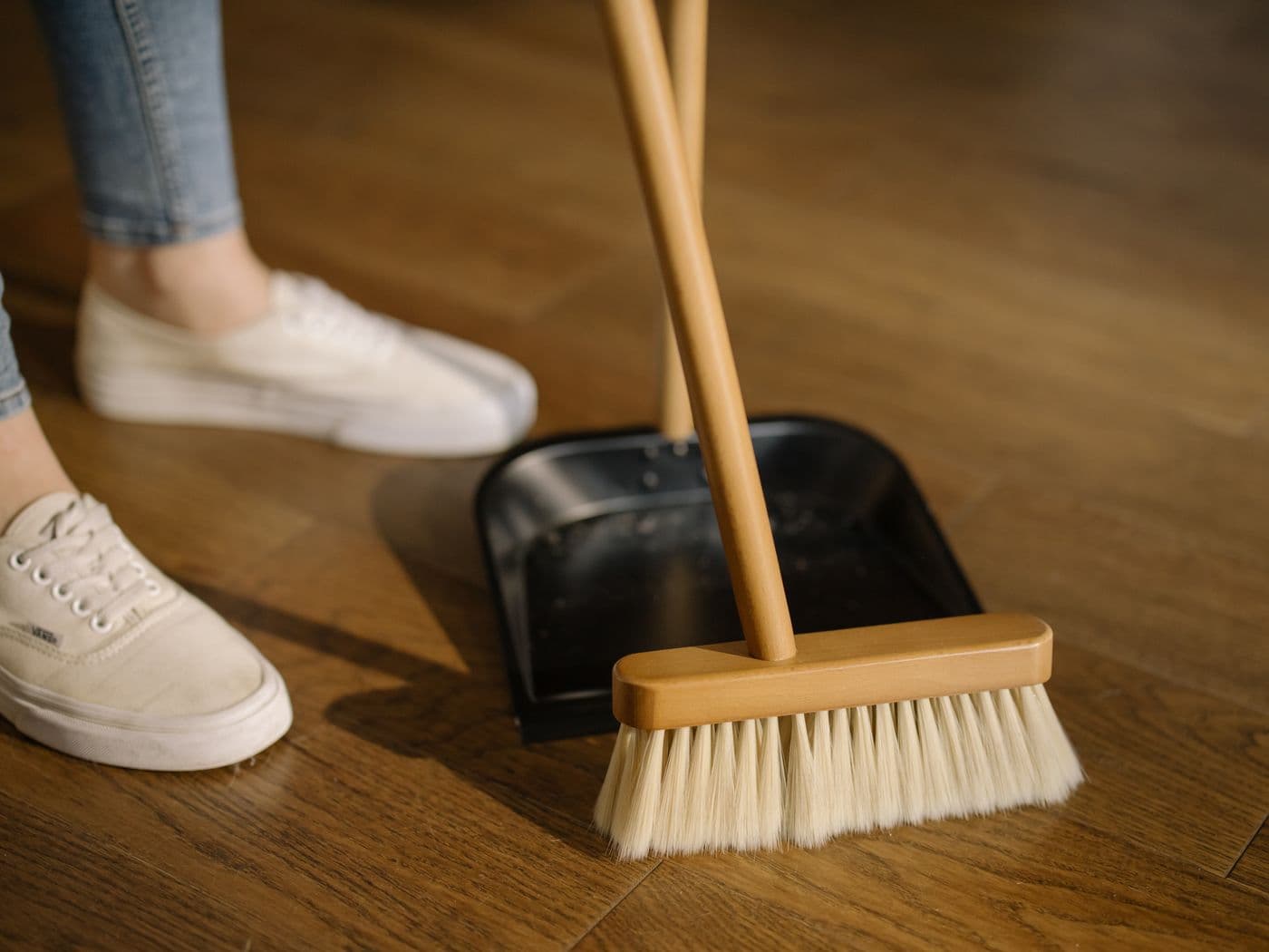 Close-up of a broom and dustpan on a hardwood floor