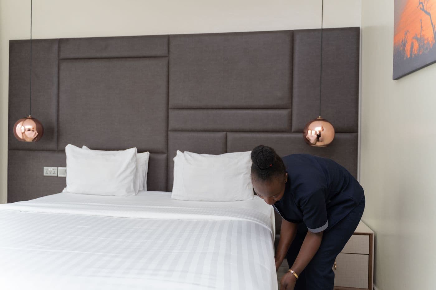 Housekeeper making a bed with fresh white linens for the next guests