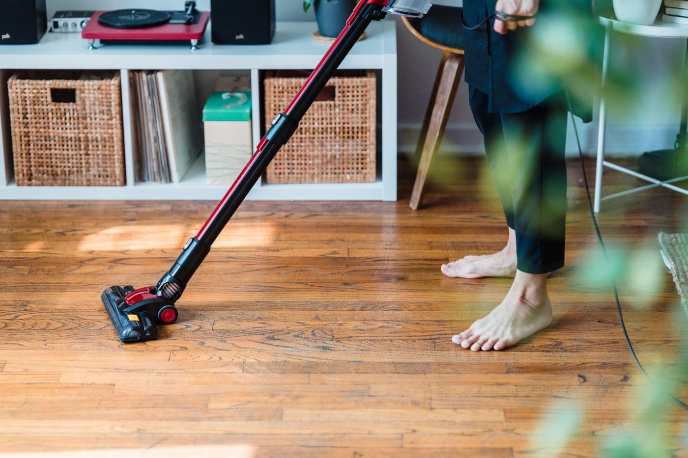 Cordless vacuum cleaning a hardwood floor in a home