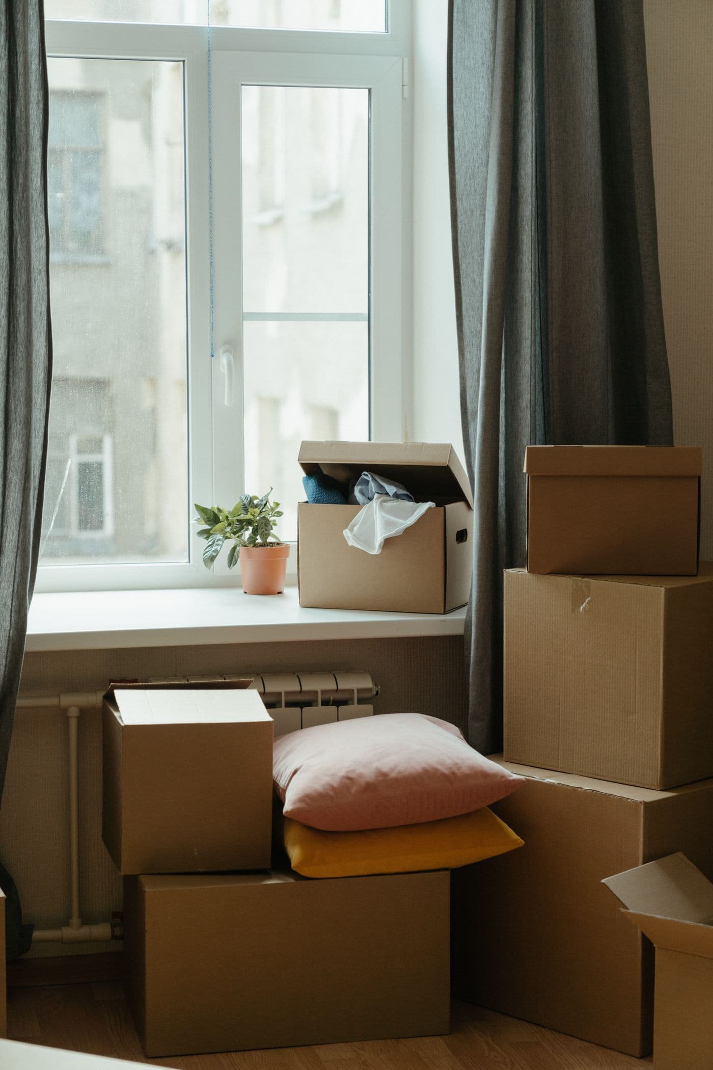 Moving box on a freshly made bed in a bright, clean bedroom