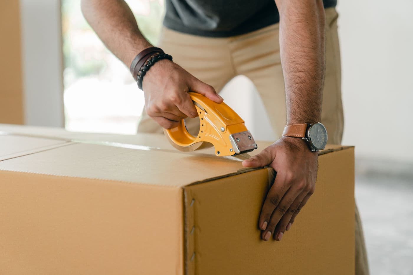 Person sealing a cardboard moving box with tape